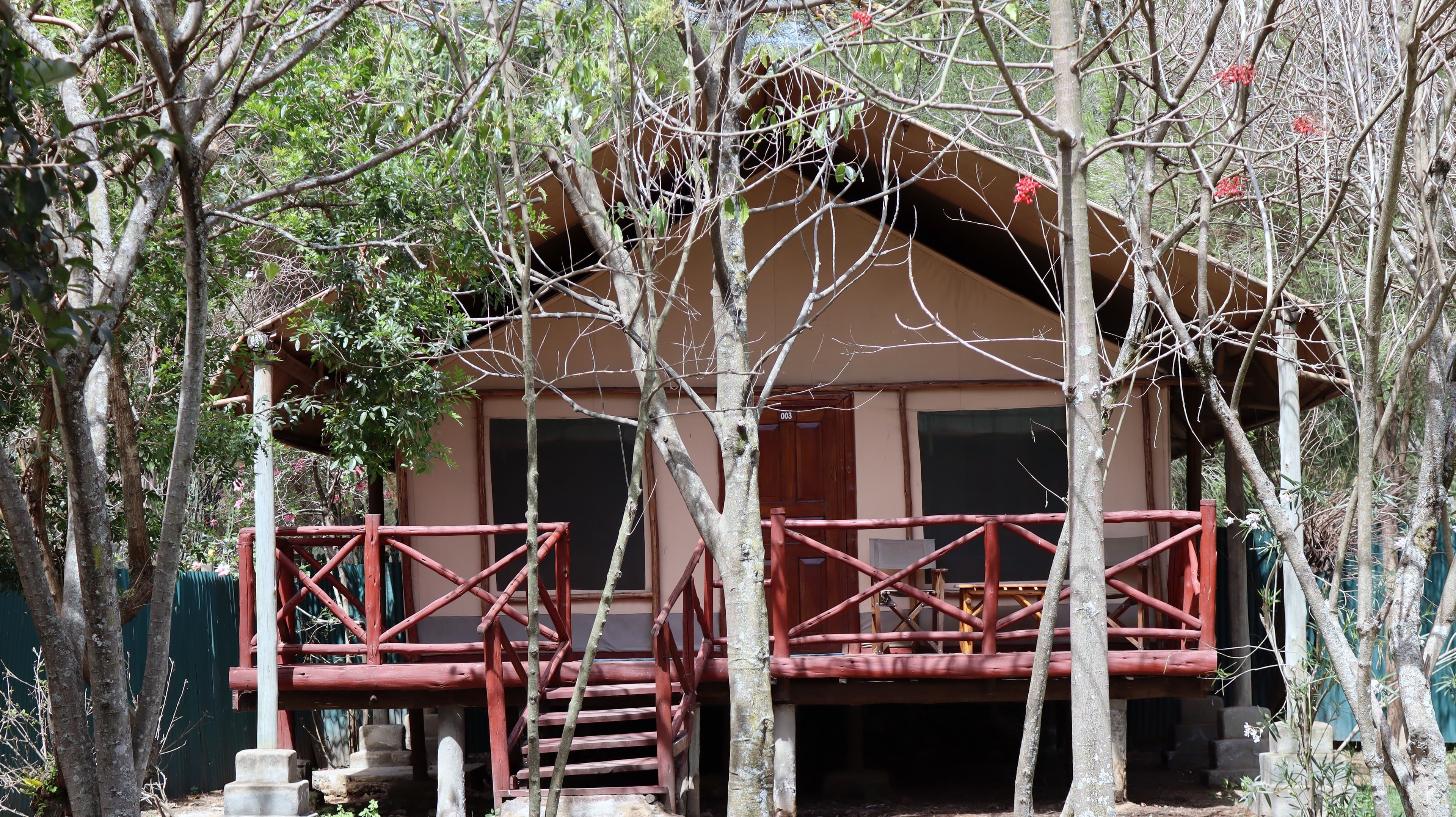 A raised tent on stilts with a timber verandah and steps at Lake Naivasha Crescent Camp