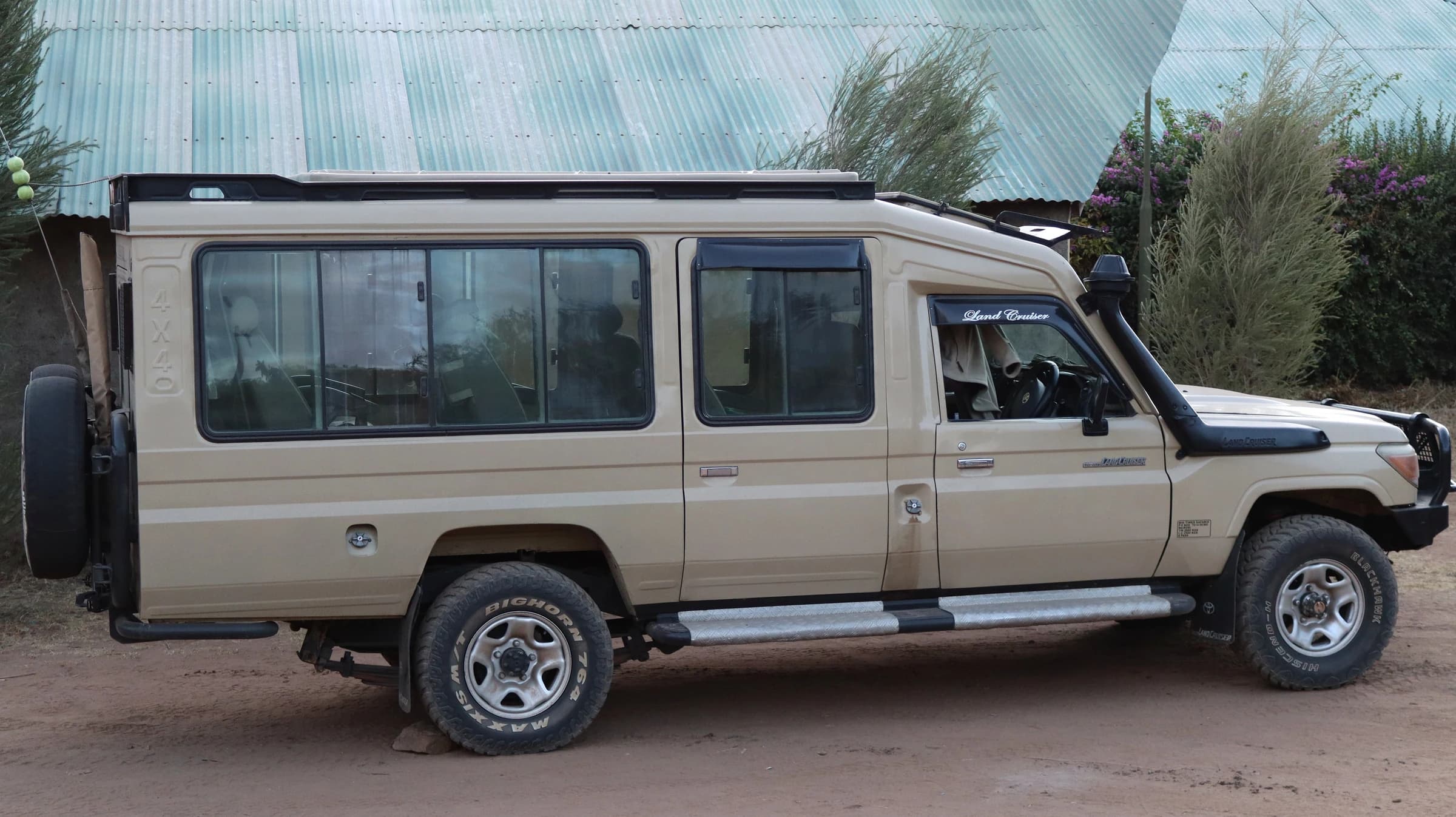 A 4×4 Land Cruiser safari vehicle with a pop-up roof, parked and ready for a game drive