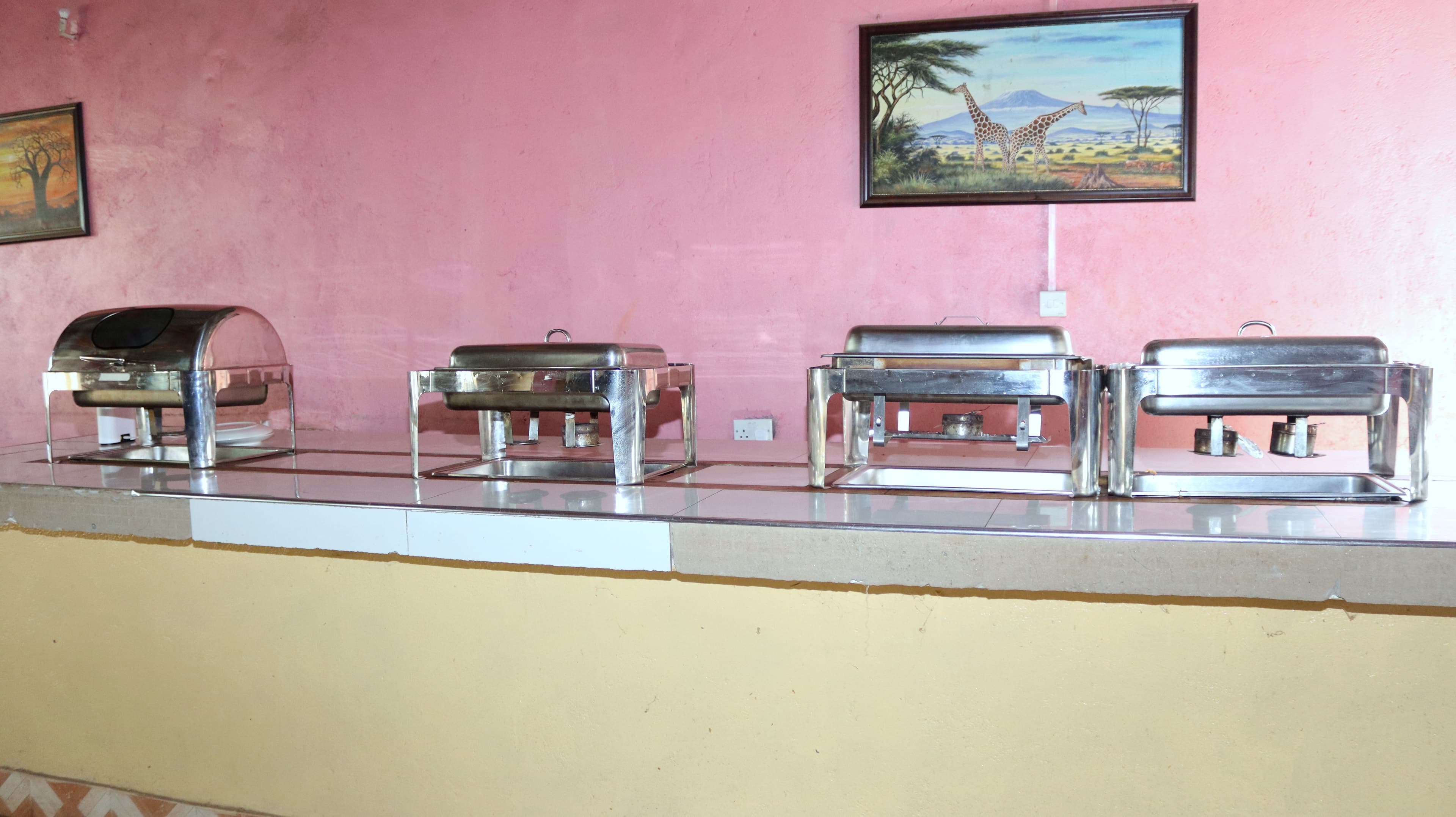A buffet counter with covered serving dishes at Miti Mingi Eco Camp