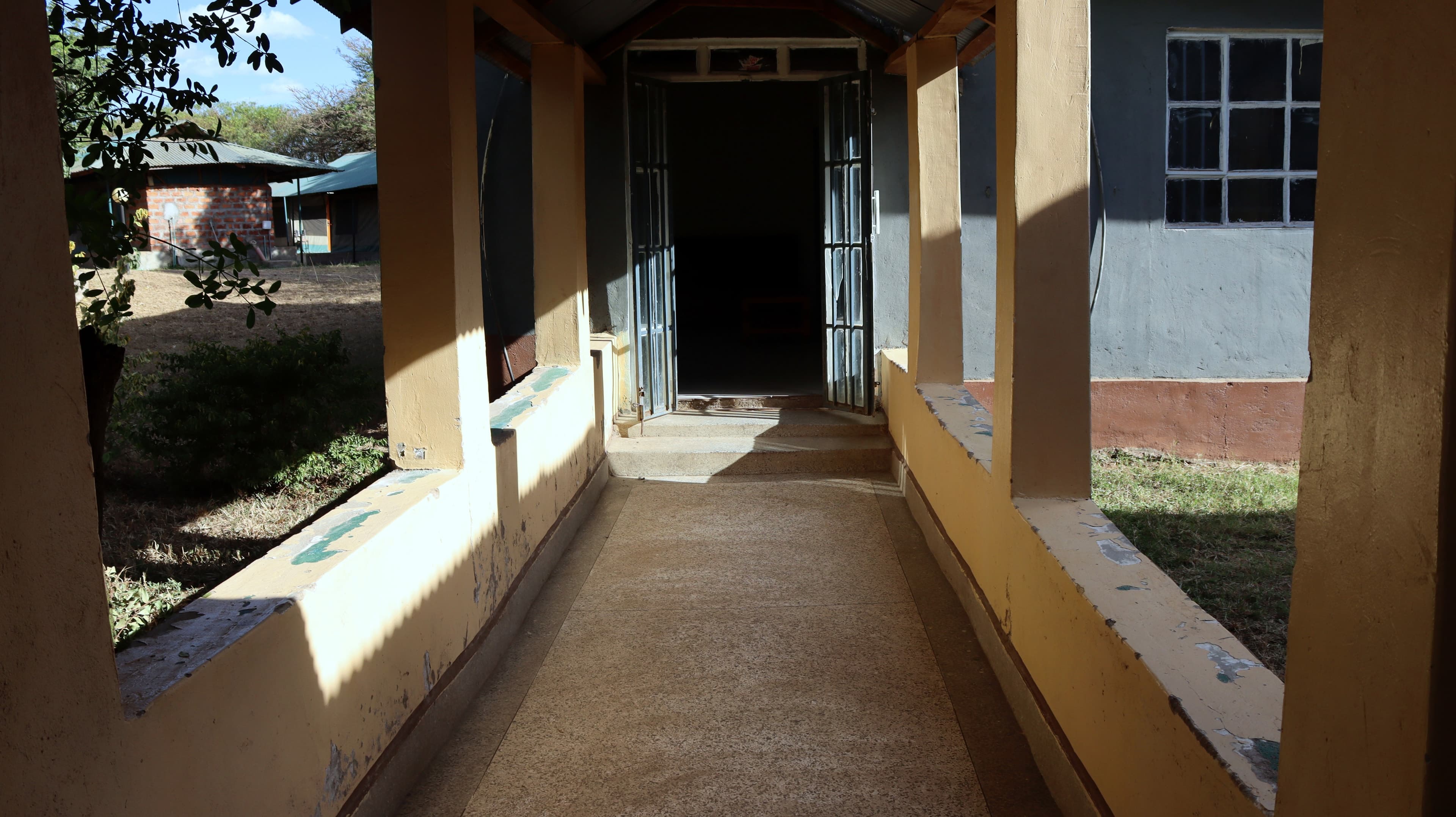 A covered walkway leading to a doorway in one of the camp buildings at Miti Mingi Eco Camp