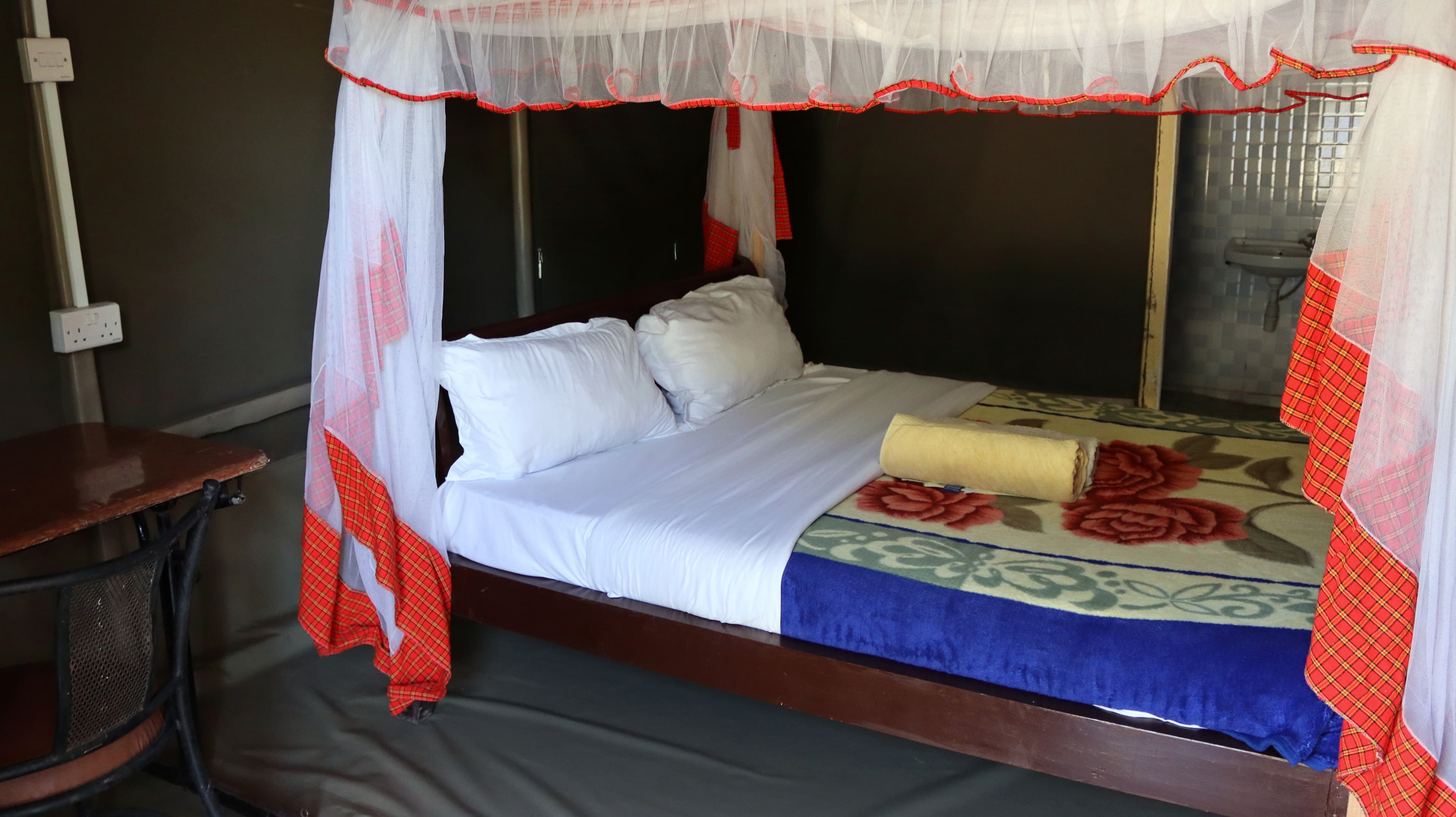 A double bed with a mosquito net and folded blanket inside a guest tent at Miti Mingi Eco Camp