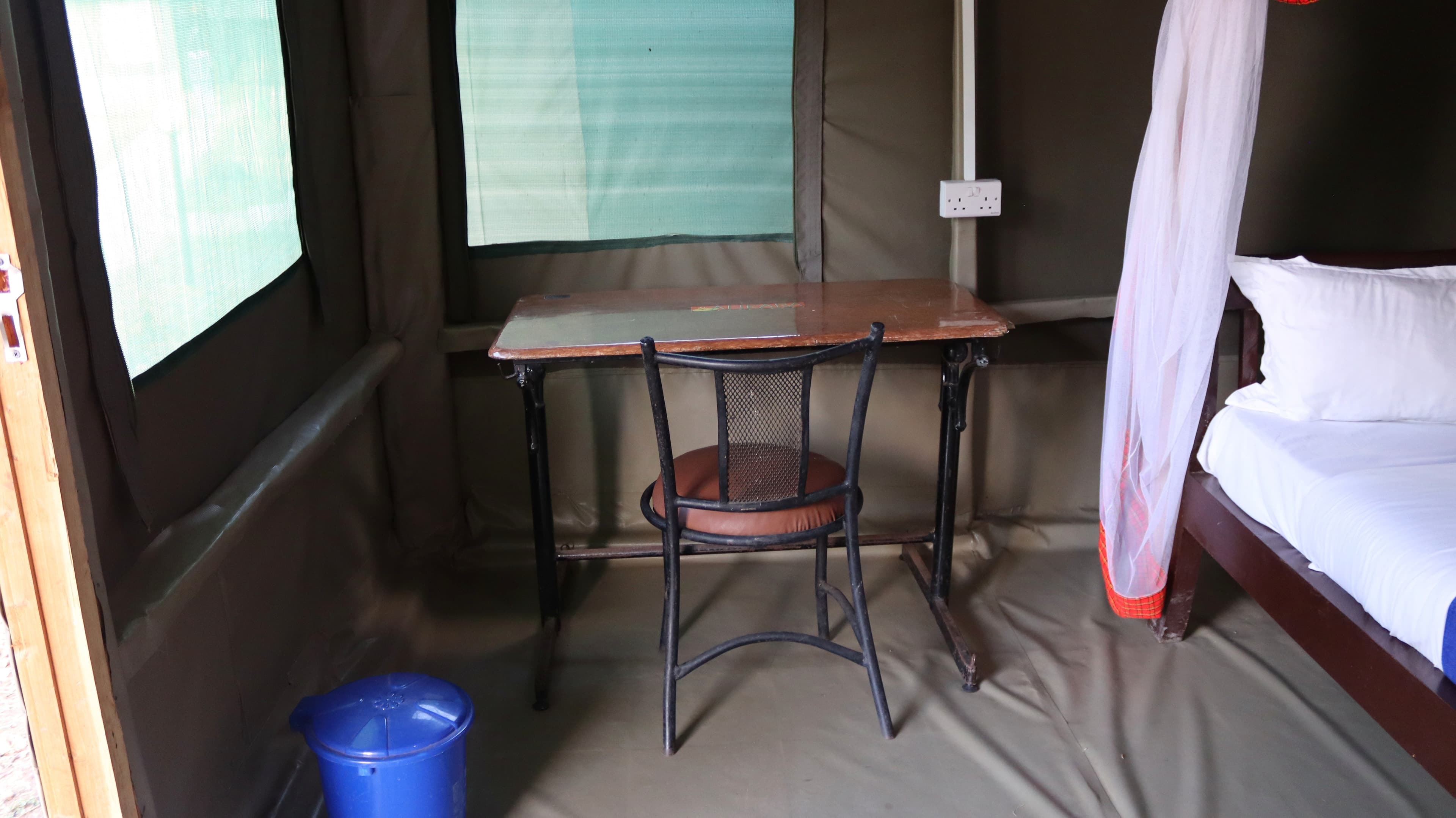 A writing table and chair beside the bed inside a guest tent at Miti Mingi Eco Camp