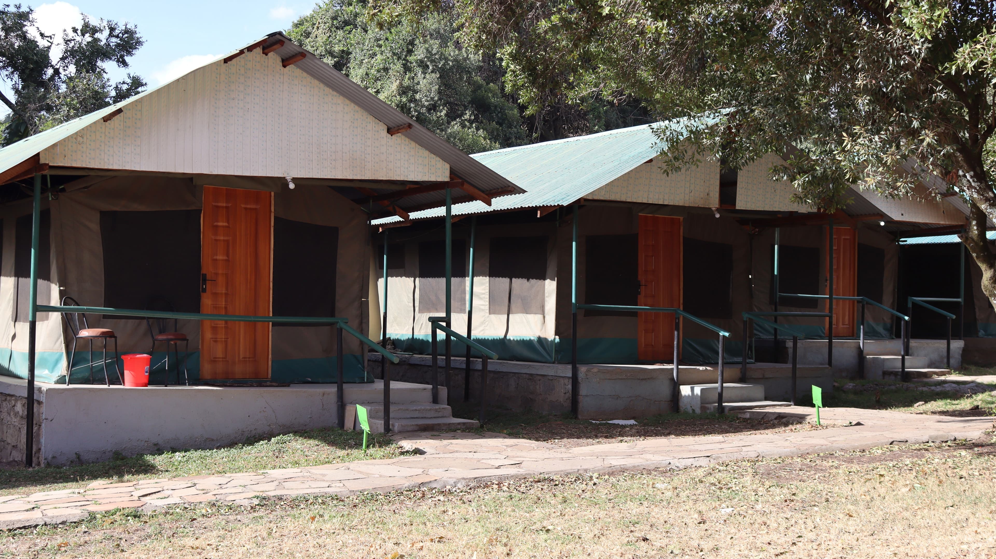 A row of canvas guest tents with verandahs and steps along a stone path at Miti Mingi Eco Camp