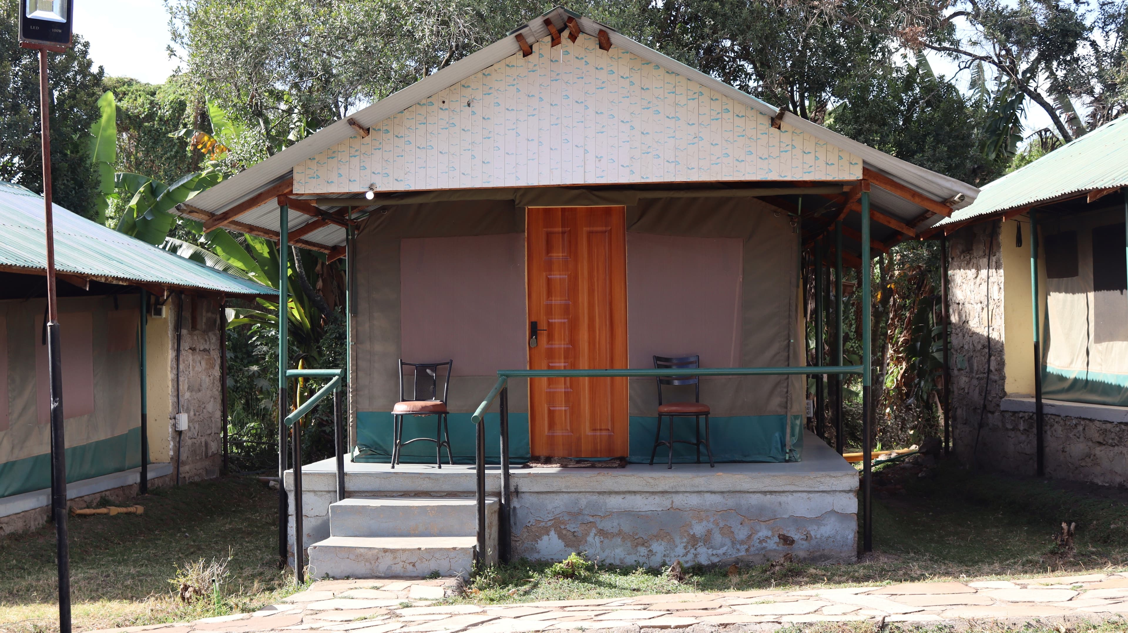 A canvas guest tent on a raised base with a covered verandah and two chairs at Miti Mingi Eco Camp